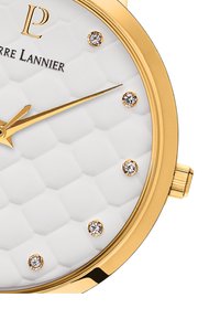 Reloj de tono dorado con un dial blanco texturizado, que presenta manecillas doradas y seis marcadores de cristal. Incluye una corona en el lado derecho para ajustes.