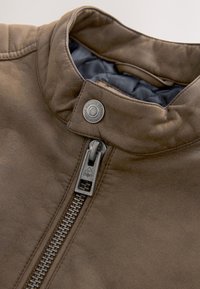 Bruine leren jas kraag met metalen rits en drukknop, met een gladde textuur en doorgestikte donkere binnenvoering.