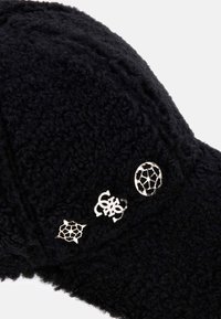 Cappello in pile nero e texture con tre spille metalliche con design geometrici. Il tessuto è morbido e peloso, creando un aspetto accogliente.