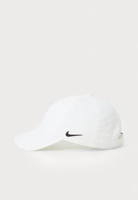 Biała bawełniana czapka baseballowa z zakrzywionym daszkiem, z czarnym logo Nike z przodu i regulowanym paskiem z tyłu.