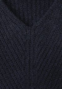 Pull en maille bleu marine foncé présentant un motif texturé avec un col en V. Le tissu semble doux et légèrement volumineux.