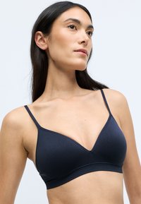 Bralette blu navy, senza cuciture, con design a coppa triangolare, spalline sottili e una texture liscia, dotato di una fascia sottostante ampia.