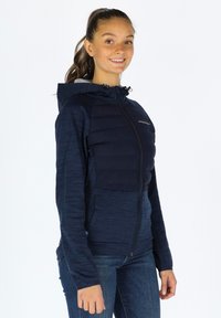 Marineblauwe rits-hoodie met een puffy borstpaneel, capuchon en textuursleeves. Voorzien van een gladde afwerking en contrasterende donkerblauwe accenten.