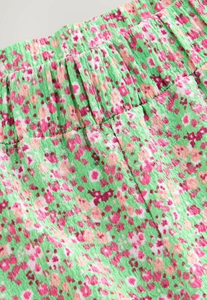 Tissu vert avec un motif floral dans des tons de rose, blanc et pêche. Comprend une taille élastique et une surface texturée.