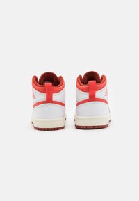 Sneaker alte bianche con accenti rossi, caratterizzate da un upper in pelle testurizzata, colletto imbottito e suola in gomma testurizzata con motivo antiscivolo.