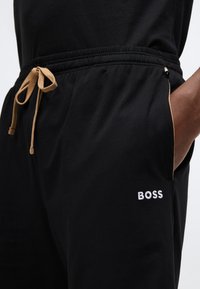 Μαύρο βαμβακερό παντελόνι jogging με ελαστική μέση με κορδόνι, πλαϊνές τσέπες με καφέ λεπτομέρειες και λευκό κεντητό λογότυπο "BOSS".