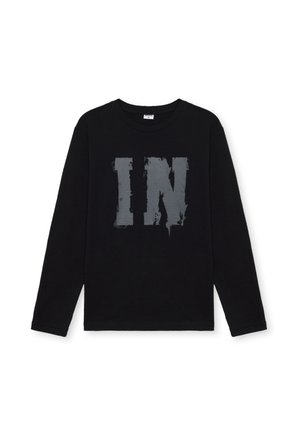 Camiseta de manga larga negra hecha de algodón, con una gran impresión plateada desgastada "IN" en la parte frontal. Cuello redondo, talle estándar.