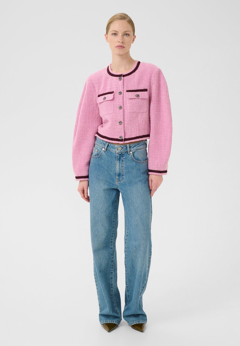 Rosa tweed kort jacka med två framfickor och mörk trim, matchad med ljusblå hög midja raka jeans och spetsiga olivgröna klackar.
