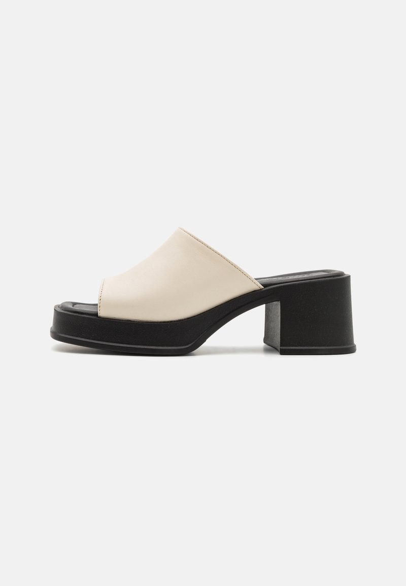 Mule beige à enfiler avec bout ouvert, semelle plateforme noire épaisse et talon bloc épais, présenté sur un fond clair uni.