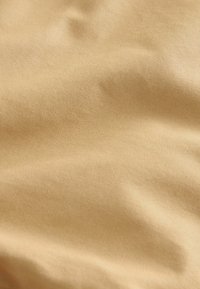 Beige stof met een gladde textuur, met een subtiele glans en een fijn ribbelpatroon over het oppervlak. Zacht en valt gemakkelijk.