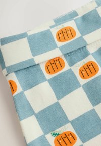 Tissu à carreaux bleu et blanc avec de petites citrouilles orange présentant des visages souriants et des tiges vertes dans certains carrés.