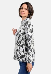 Pullover aus schwarz-weißem Stoff mit floralem und abstraktem Muster, Rundhalsausschnitt, langen Ärmeln und lockerem Schnitt.