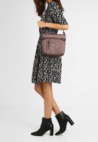 Dunkelgraue Schultertasche mit zwei oberen Reißverschlüssen und einem verstellbaren Tragegurt, aus Leder mit glatter Textur und minimalistischem Design.