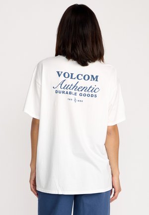 Biała bawełniana koszulka z niebieskim nadrukiem na plecach, który brzmi „VOLCOM Authentic Durable Goods”, o luźnym kroju i krótkich rękawach.
