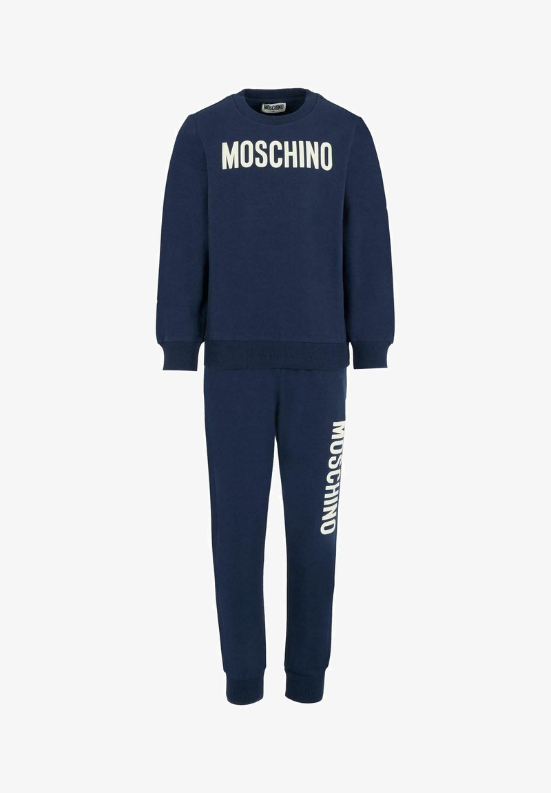 Ensemble de sweat-shirt et pantalon de jogging bleu marine avec le logo blanc "MOSCHINO" sur la poitrine et la jambe gauche, bords côtelés aux poignets et à l'ourlet.