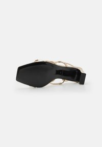 Sandalo con tacco nero e oro metallizzato, caratterizzato da una punta quadrata, un design minimalista con cinturini e una suola nera liscia.