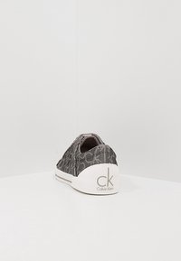 Grijze stoffen sneaker met CK-logo, laag profiel en gestructureerd oppervlak, witte zool. Zonder veters, instapmodel. Minimalistische stijl.