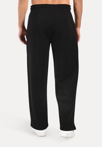 Black elastic waistband pants with a loose fit and soft texture, featuring straight legs and no visible patterns or accents.