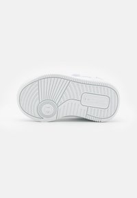 Biała podeszwa sneakersów z teksturowanymi rowkami, okrągłym logo i żłobioną krawędzią dla lepszej przyczepności. Gładki materiał i minimalistyczny design.