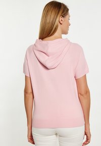 Lichtroze hoodie met korte mouwen van zachte brei stof. Heeft een losse pasvorm en een ronde zoom met ribgebreide accenten rond de capuchon en onderkant.