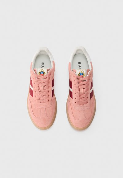 Baskets en suède rose avec des rayures latérales bordeaux et blanches, bout rond, devant à lacets et semelle en caoutchouc brun clair. Comprend un logo sur la languette.