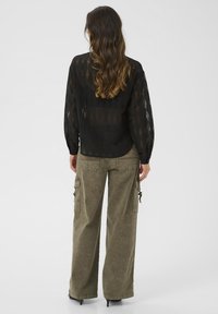 Black lace blouse with a diamond pattern, paired with olive-green cargo pants featuring side pockets and a relaxed fit.