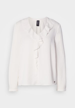 Blouse blanche à manches longues avec un col à volants, texture de tissu douce et un petit logo en accent à l'ourlet.