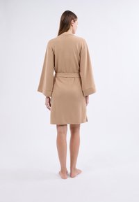 Accappatoio in cotone marrone chiaro con maniche a tre quarti e cintura, caratterizzato da una vestibilità rilassata e una texture liscia.