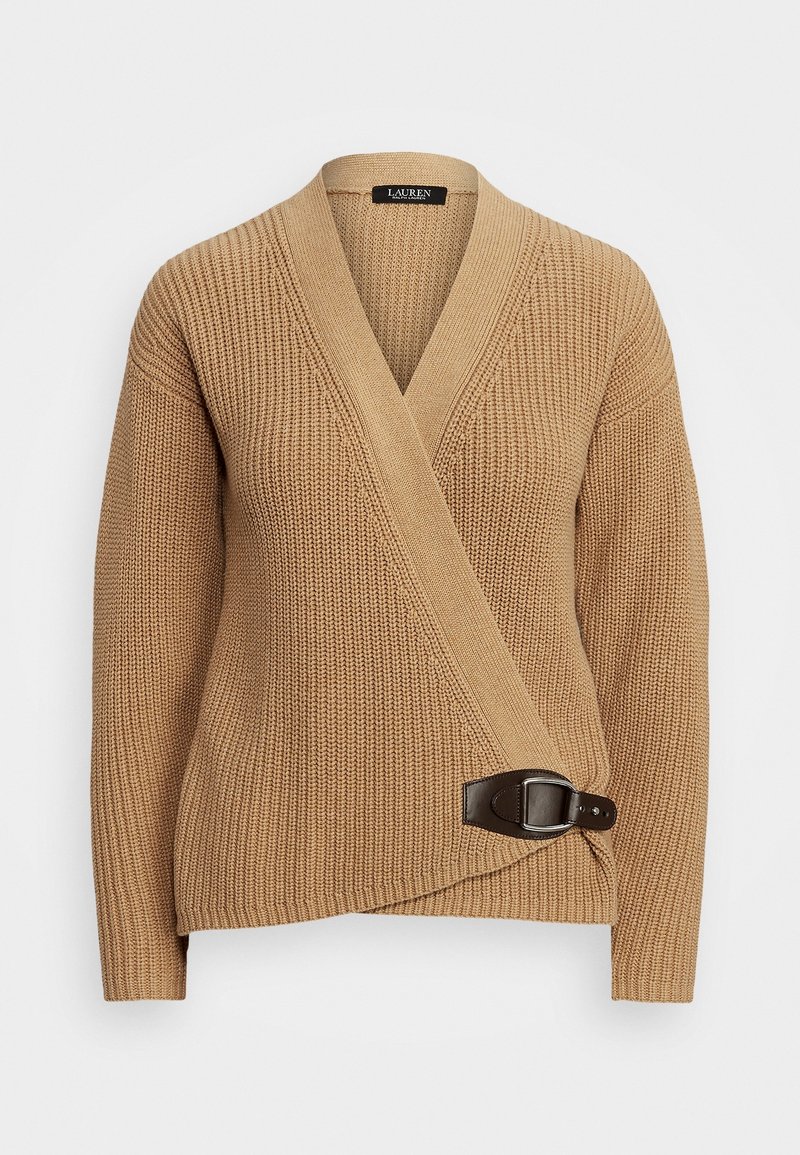 Pull en tricot beige avec un design enveloppant, présentant un détail de boucle en cuir marron à la taille. Encolure en V et manches larges.
