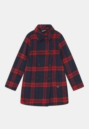 Manteau croisé à motif à carreaux rouge et bleu marine, manches longues et large col, posé à plat sur fond blanc.