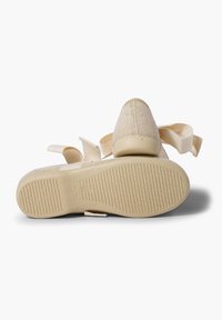 Zapato de tela beige con un upper texturizado y una suela de goma sólida. Cuenta con correas de tela para un ajuste seguro. Diseño de punta ligeramente redondeada.