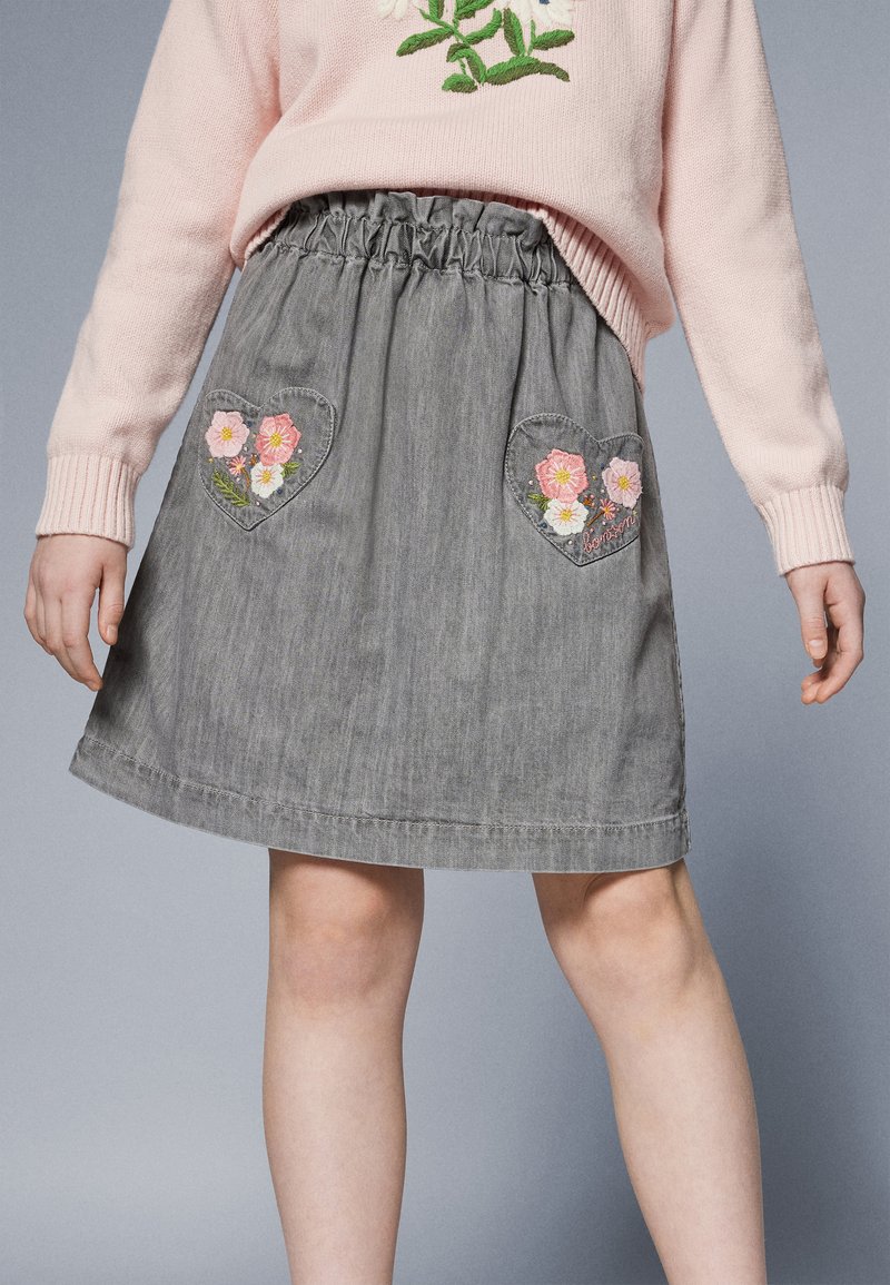 Grå denimskjørt med elastisk midje, med to hjerteformede lommer med rosa blomsterbroderi. Glatt tekstur, kne-lengde design.