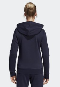 Sudadera azul marino con capucha amplia, puños y dobladillo acanalados. Presenta una textura suave y un diseño minimalista sin logotipos visibles.