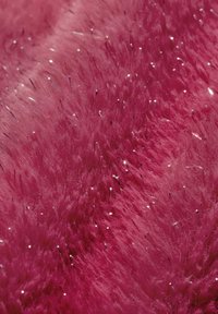 Gros plan sur une texture duveteuse dense et rose vif avec de petites paillettes argentées réfléchissantes éparpillées créant un effet scintillant.
