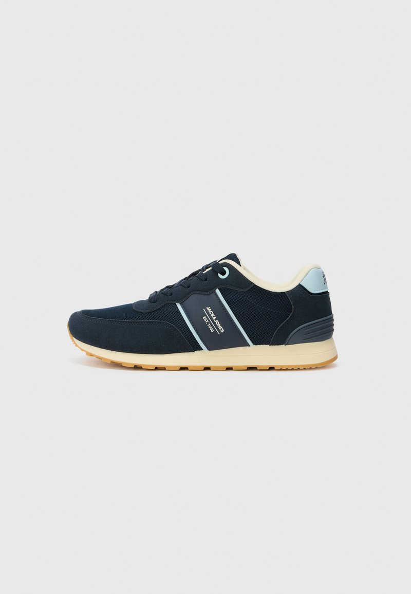 Sapatos atléticos azul-marinho feitos de camurça e malha, com um detalhe em creme no calcanhar e sola em borracha de goma. Logotipo lateral e design com atacadores.