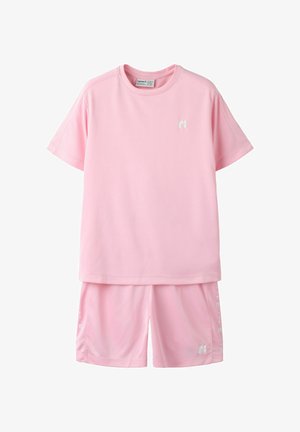 Chemise à manches courtes rose pâle et short assorti avec de petits logos blancs sur la poitrine et la jambe, posés à plat sur un fond blanc.