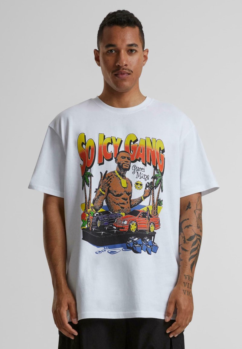 Hvid bomulds t-shirt med et farverigt grafisk design af en muskuløs figur, biler, palmer og teksten "SO ICY GANG" i fede bogstaver.