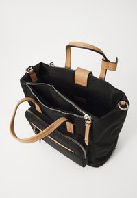 Black fabric bag with tan leather accents, featuring multiple zippered compartments and short handles for carrying.