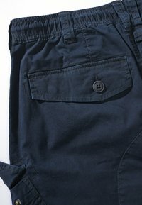 Pantalones cargo azul marino con una tela texturizada, que cuentan con una cintura elástica, un bolsillo lateral y un bolsillo trasero con un detalle de botón negro.