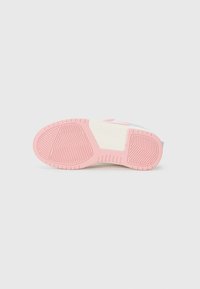 Semelle de sneaker avec un fond en caoutchouc rose et un motif en chevron, une semelle intermédiaire couleur crème et des accents bleu clair sur le bord supérieur.