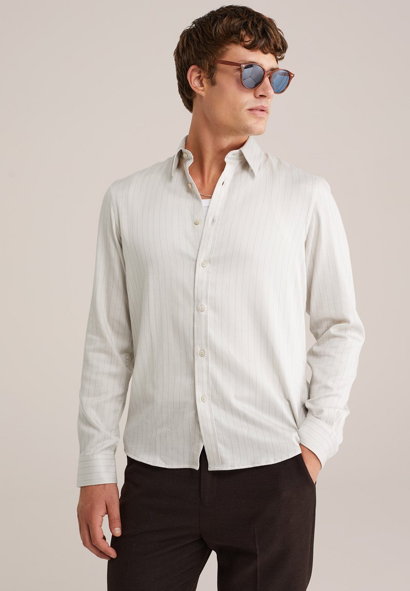 Lichtgrijze button-up overhemd met dunne verticale strepen, lange mouwen en een klassieke kraag, gecombineerd met donkere broek.