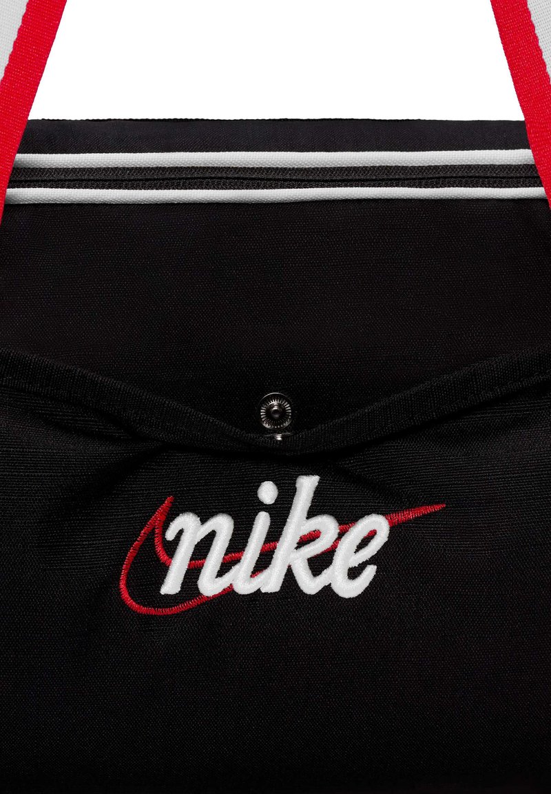 Borsa di stoffa nera con spalline rosse, linee con zip bianche e testo 'nike' ricamato in bianco con logo swoosh rosso.