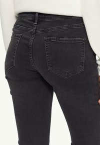 Mustad denim teksad kõrge vöökohaga, kahe tagataskuga ja kerge kulumise tekstuuriga. Õmmeldud detailid vöökoha ümber.