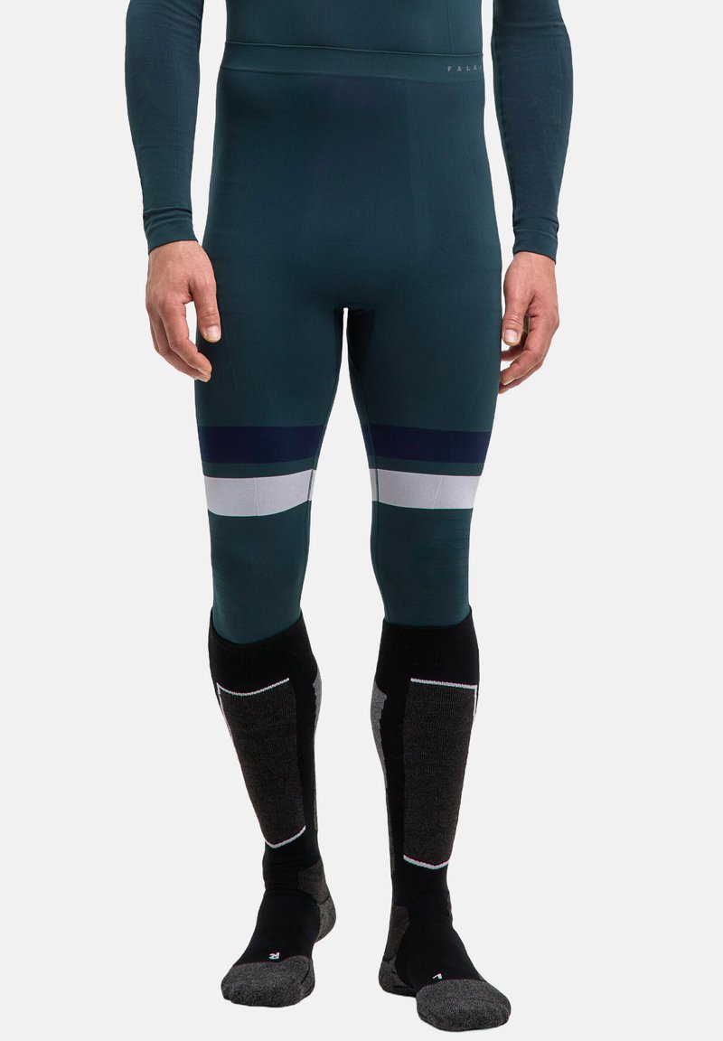 Eng anliegende thermische Leggings in tiefem Teal mit weißen und marineblauen Streifen. Kombiniert mit hohen Socken, die graue und schwarze Akzente aufweisen.
