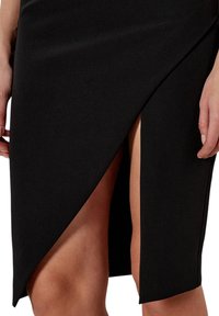 Gonna a matita nera con uno spacco alto, realizzata in un tessuto morbido. Caratterizzata da un design aderente e dettagli in cuciture diagonali.