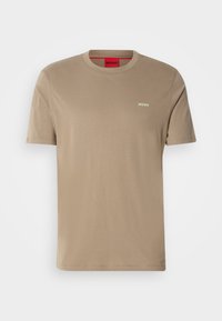 Beige T-shirt med korte ærmer og rund hals, med "HUGO" logo på venstre bryst og rød label på indersiden af halsen.