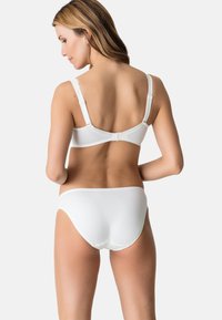 Biały zestaw bielizny z gładkiego, elastycznego materiału; regulowane ramiączka w biustonoszu; falbany na krawędziach zarówno biustonosza, jak i majtek.