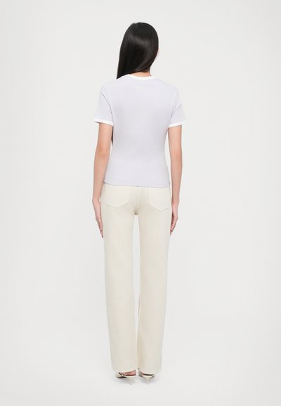 Tricou alb cu manșon scurt și decolteu rotund, asortat cu pantaloni largi crema. Textură netedă cu detalii de design minime.