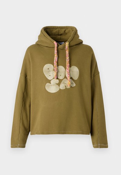 Olivovo zelená mikina s uvoľneným strihom, s veľkým grafikou v zlatej farbe a farebnými textúrovanými šnúrkami. Šité detaily pozdĺž švov.