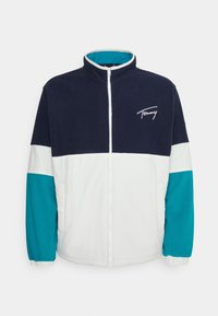 Kurtka na zamek; posiada granatowo-biało-turkusowy design w blokach kolorów; miękka w dotyku; haftowane logo na piersi; kołnierz stójka.